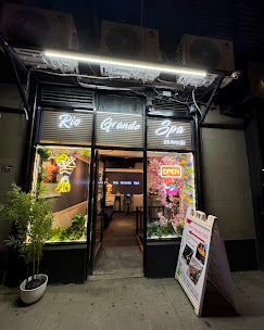 Rio Grande Spa storefront glowing at night on Ann Street in Lower Manhattan